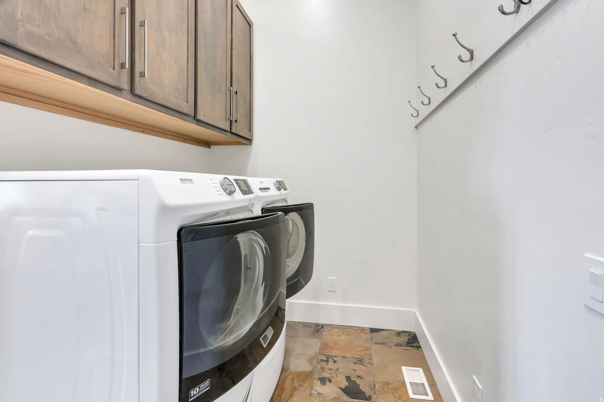 Built-in wood cabinetry with metal hardware, slate-look tile flooring, and integrated wall hooks