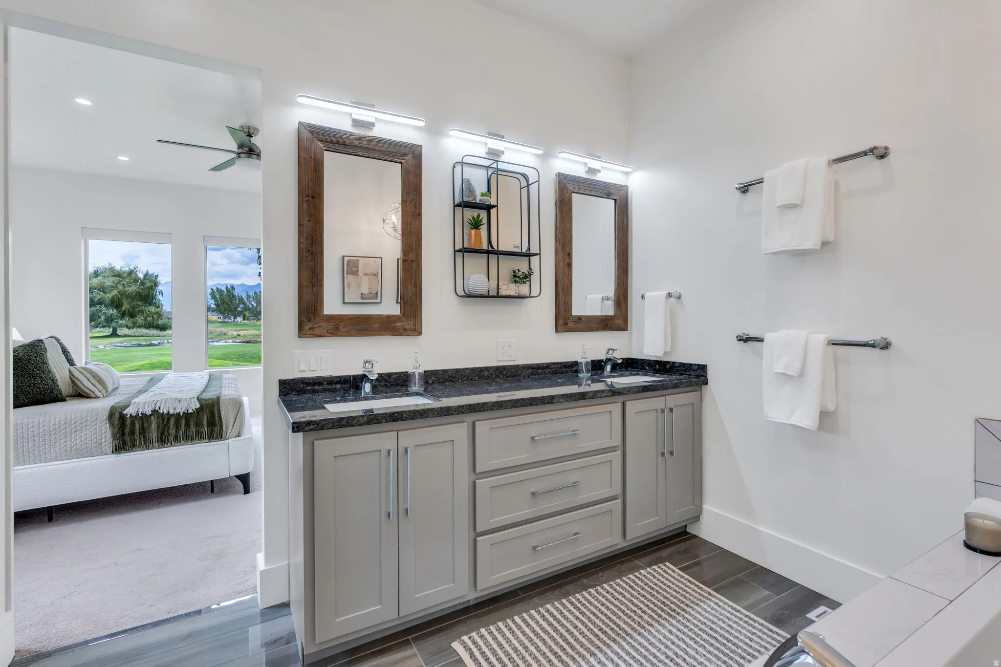 Dual vanity with dark granite-style countertop, undermount sinks, and light gray cabinetry