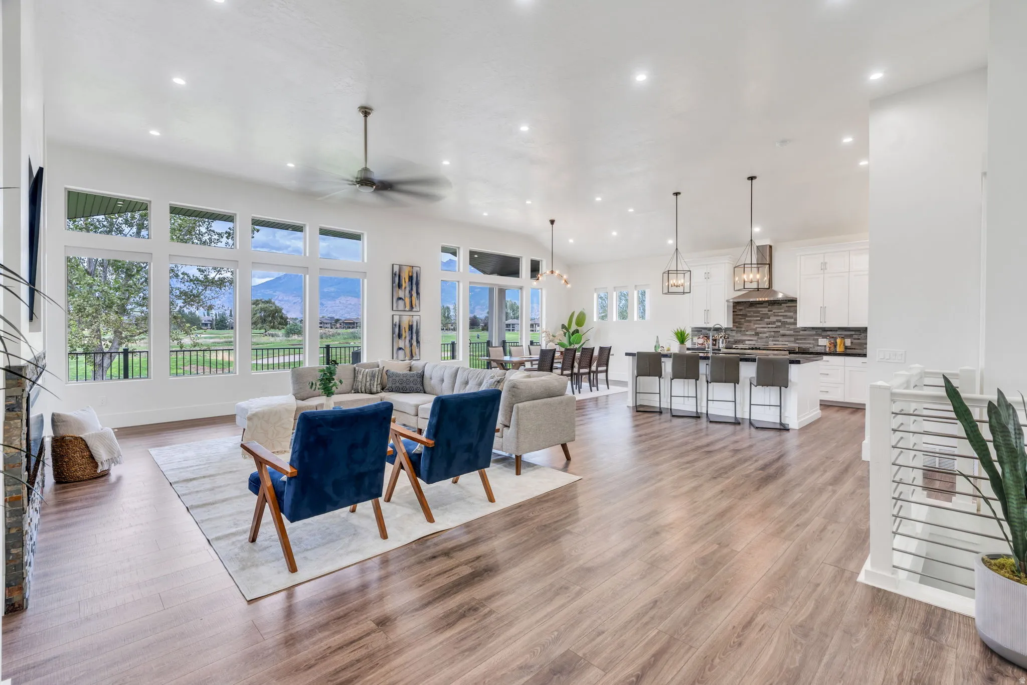 Expansive living area featuring wood-finish flooring, a contemporary ceiling fan, and large windows