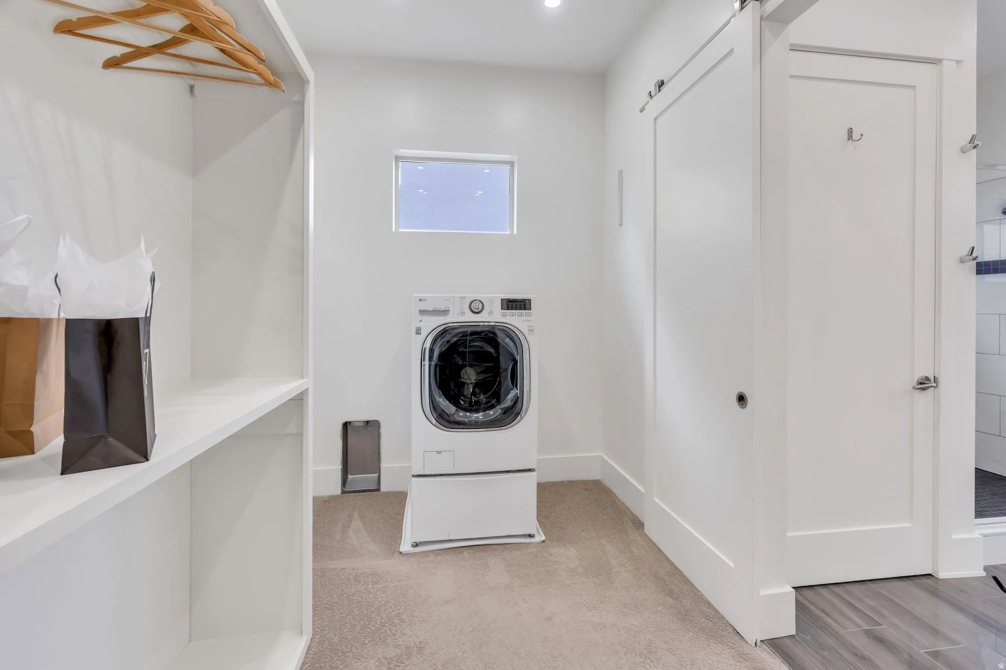 Integrated laundry area with shelving, a compact window, and a sliding barn door