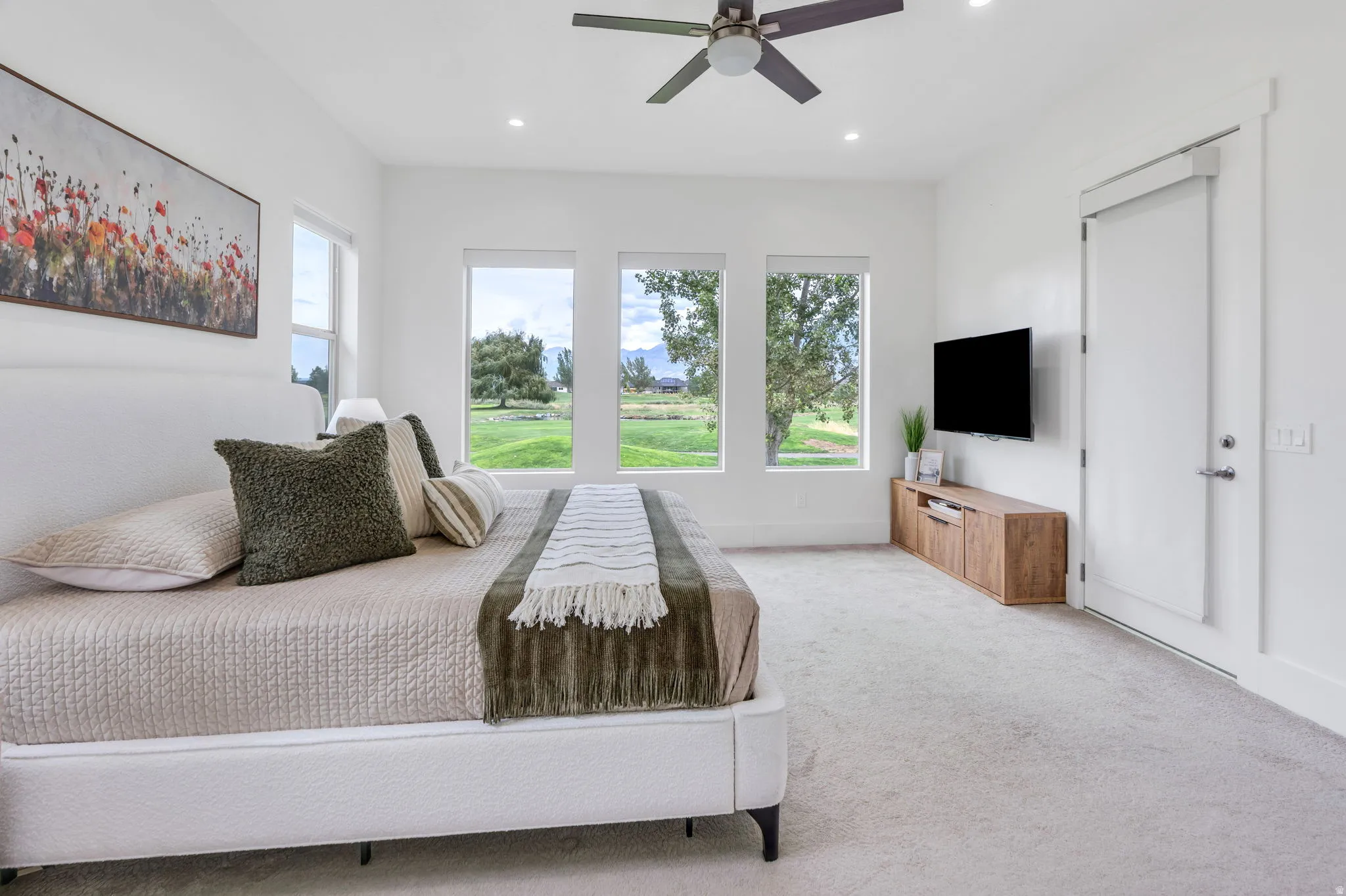 Light-filled space featuring three large windows, a ceiling fan, recessed lighting, and light-toned carpeting