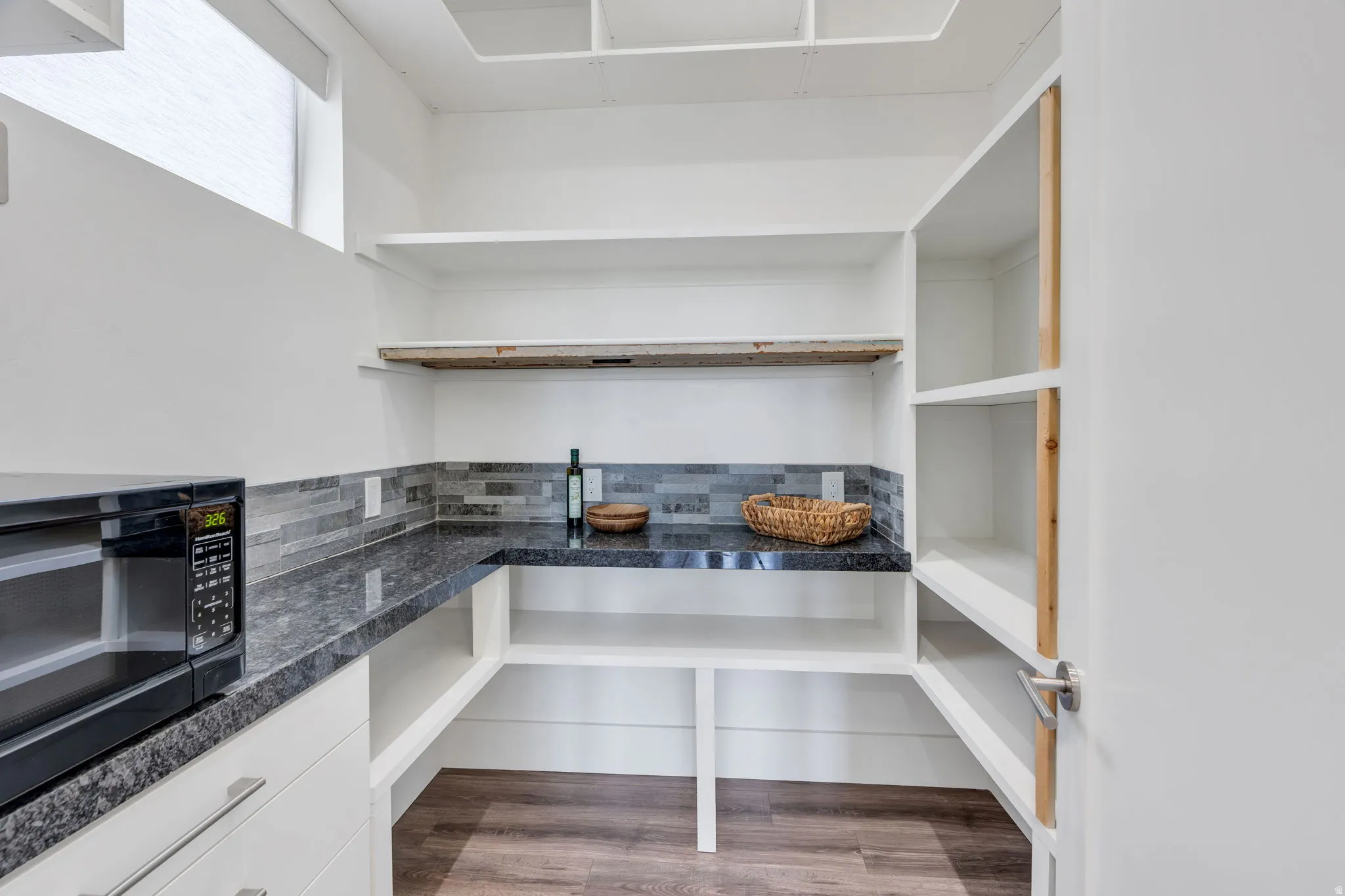 Built-in shelving, dark-toned countertops, and multi-toned tile backsplash