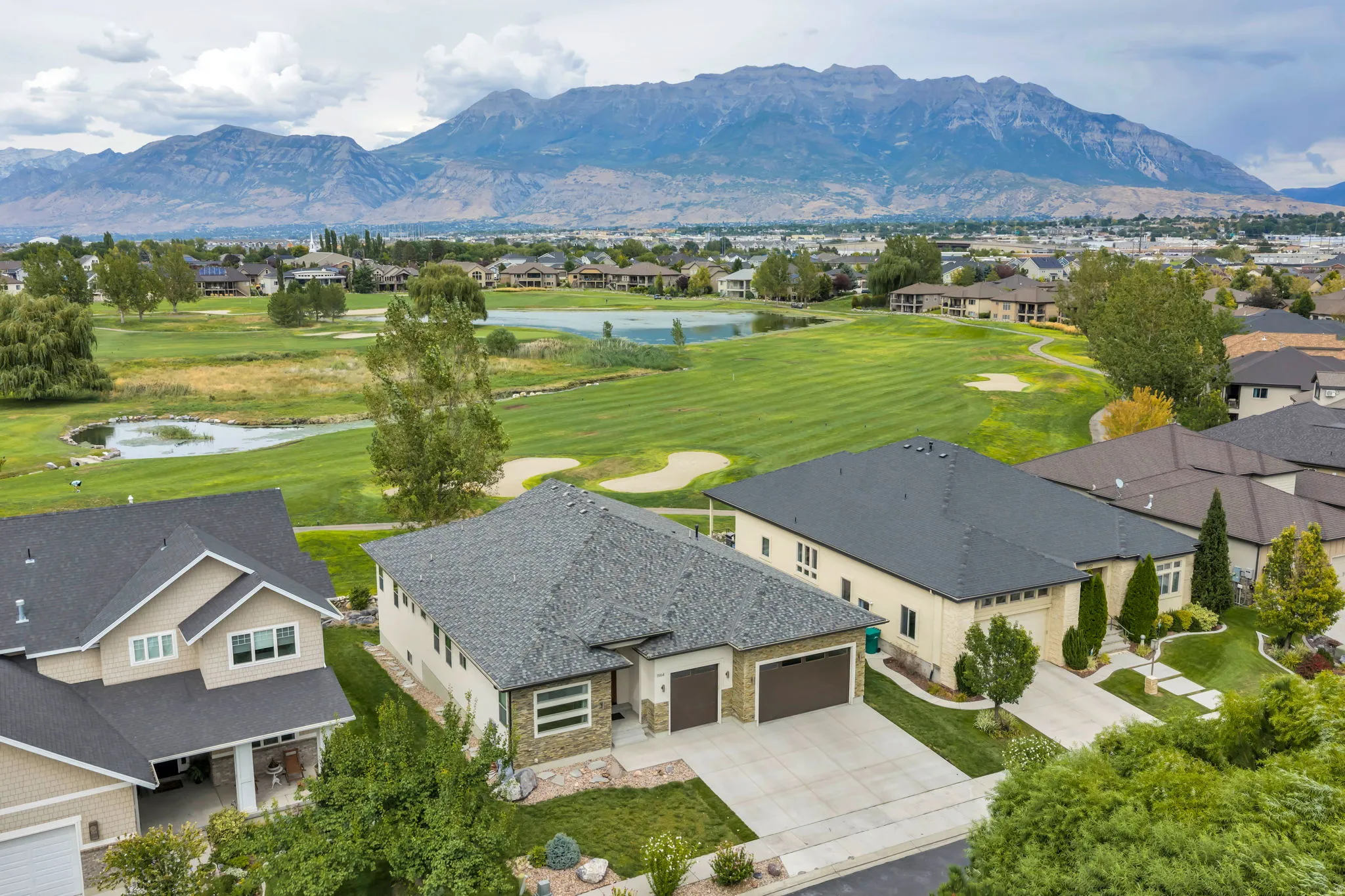 Two-car garage with a paved driveway, stone accents, and manicured landscaping