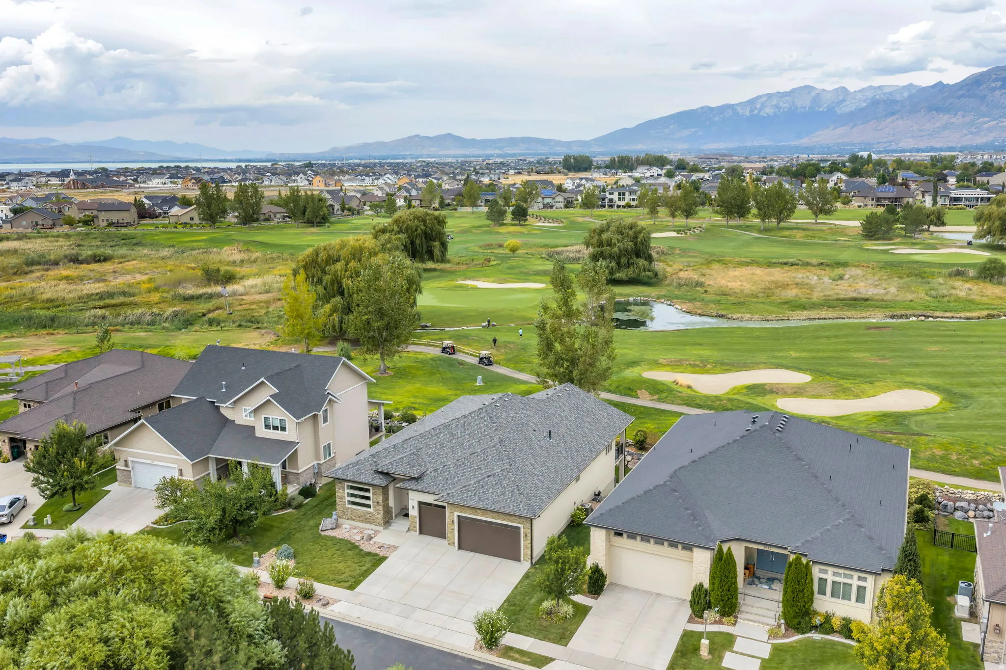 Residential properties situated alongside a golf course with mountainous backdrop and water body