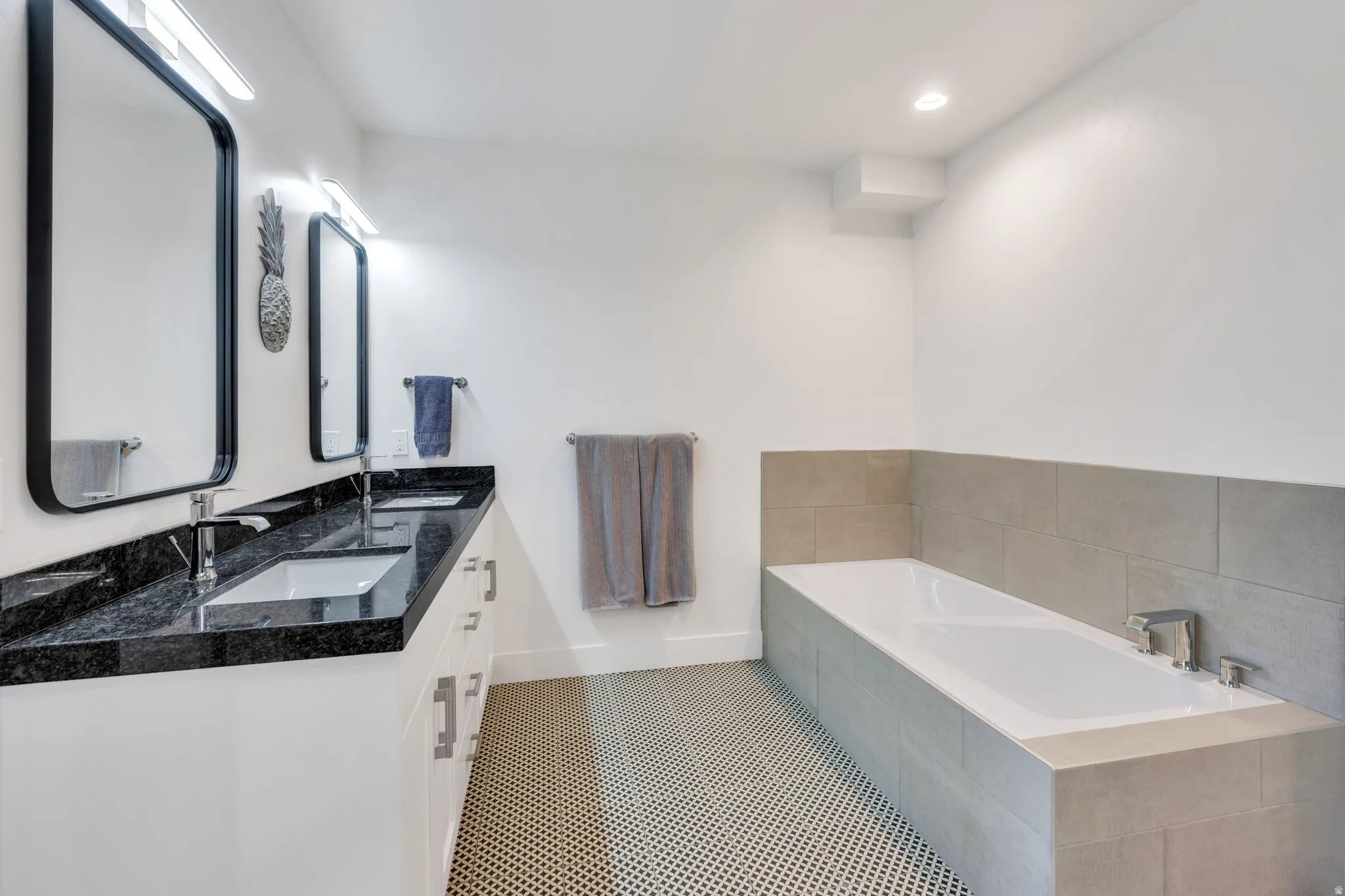 Dual vanity with dark granite countertops, white cabinetry, and undermount sinks