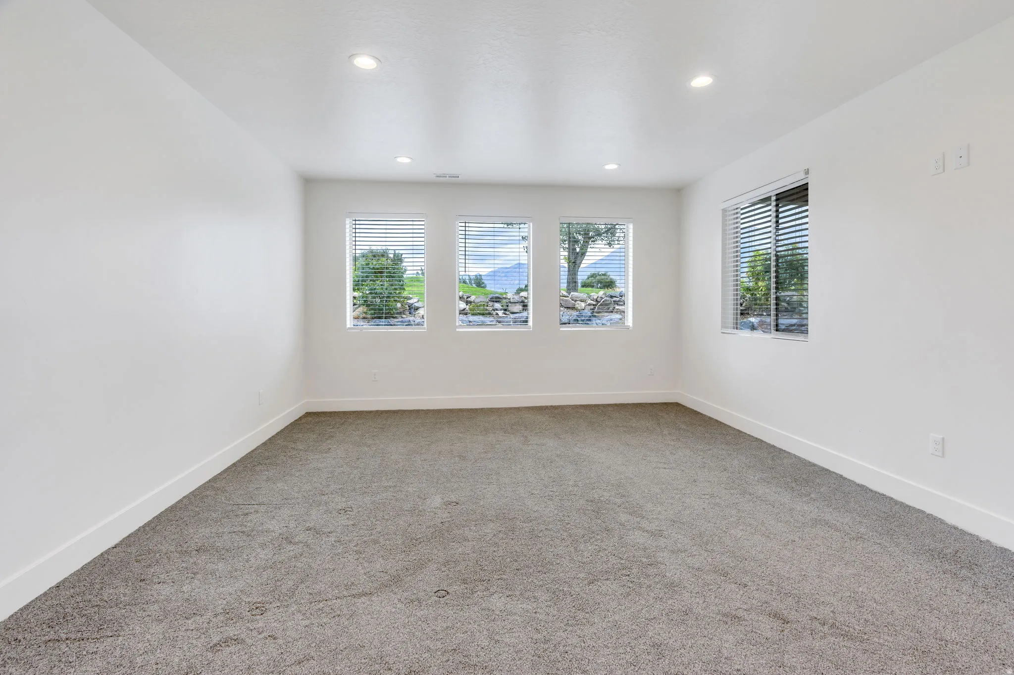 Recessed lighting illuminates neutral carpeting and white walls