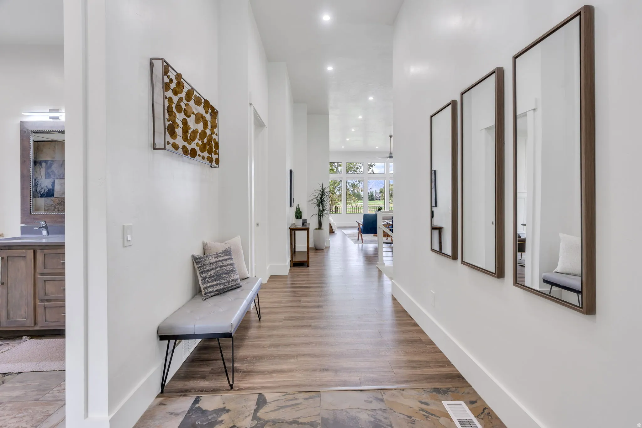 Recessed lighting, wood-finish flooring, stone tile flooring, white walls, and a built-in vanity with a rectangular sink