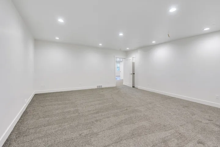 Spacious room featuring neutral carpeting, recessed lighting, and white painted walls