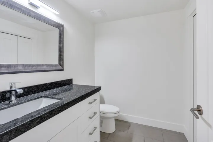 Modern bathroom featuring a floating vanity with dual sinks, polished stone countertop, and chrome fixtures