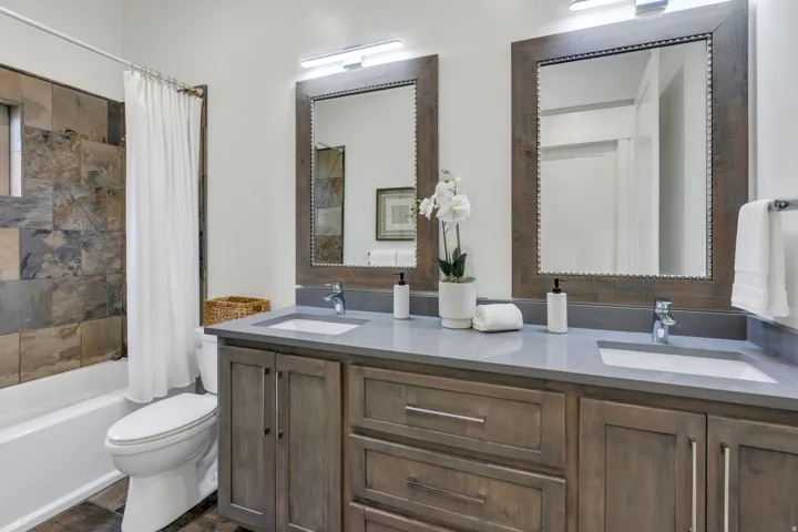 Dual vanity with integrated sinks, light gray countertop, and distressed wood-finish cabinetry