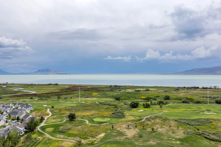 Expansive golf course frontage with winding cart paths, bordering a tranquil lake with distant mountains