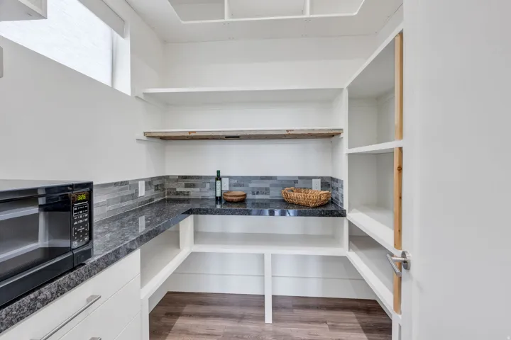 Built-in shelving, dark-toned countertops, and multi-toned tile backsplash