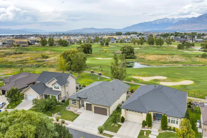 Residential properties situated alongside a golf course with mountainous backdrop and water body
