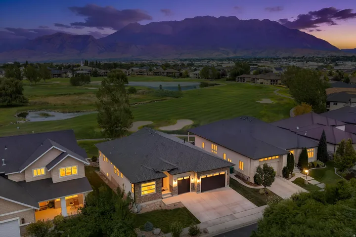 Expansive golf course setting featuring a water hazard and sand traps, with mountain scenery in the background