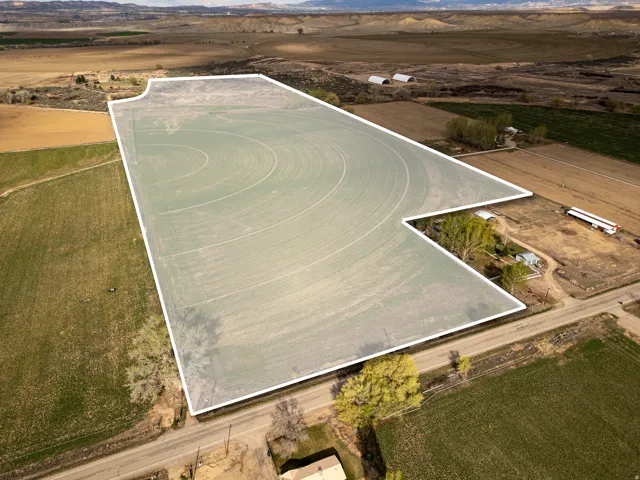 Expansive agricultural land featuring a center pivot irrigation system and surrounding natural terrain