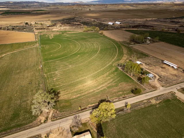 Expansive agricultural property featuring cultivated fields, circular irrigation patterns, and multiple outbuildings