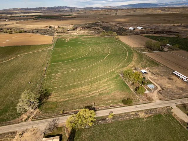 Expansive agricultural land featuring a circular irrigation system, multiple outbuildings, and a surrounding rural landscape