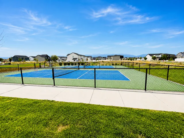 Community fenced pickleball court featuring two playing areas, a concrete path, and surrounding green space