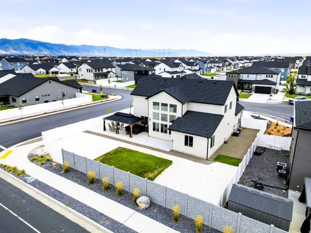 Modern exterior with multiple large windows, a covered patio structure, and a fenced yard with a combination of gravel and lawn areas