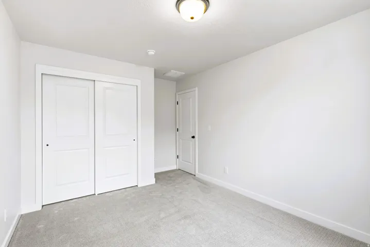 Bedroom #5 neutral wall paint, ceiling-mounted light fixture, sliding closet doors, and light-colored carpeting