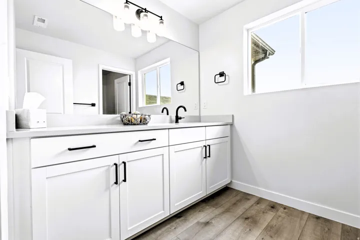 Double vanity with white cabinetry, matte black hardware, quartz countertop and an expansive mirror