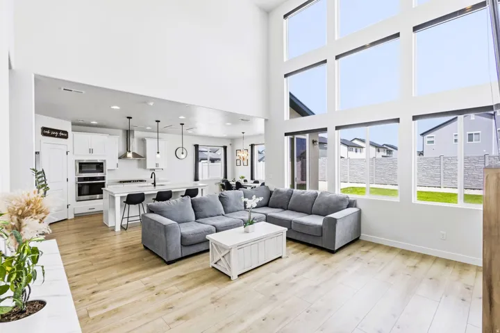 Two-story living area with expansive floor-to-ceiling windows, light wood-finish flooring, and recessed lighting