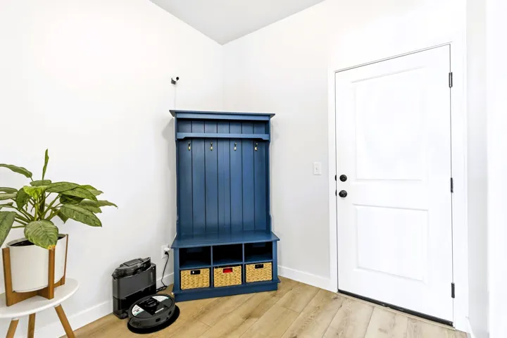 White interior door with black hardware, wood-finish flooring, and crisp white walls