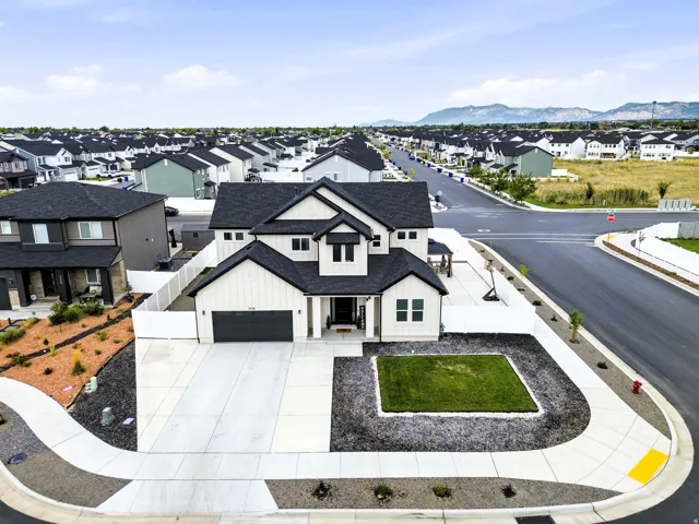 Modern exterior with contrasting dark roof and light siding, featuring an attached two-car garage, concrete driveway, and landscaped front yard