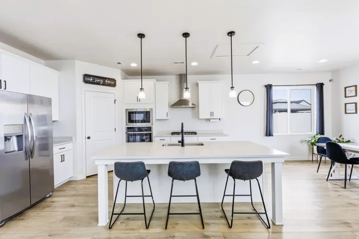 White kitchen cabinetry with stainless steel appliances, a large central island, and wood-finish flooring