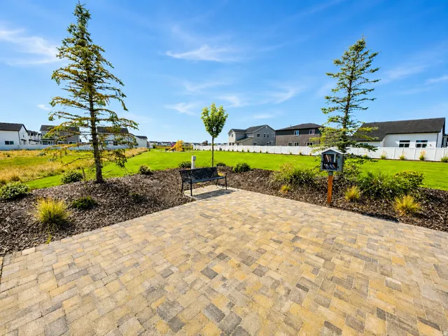 Community Park with patio area with paver flooring, a black metal bench, and surrounding landscaping