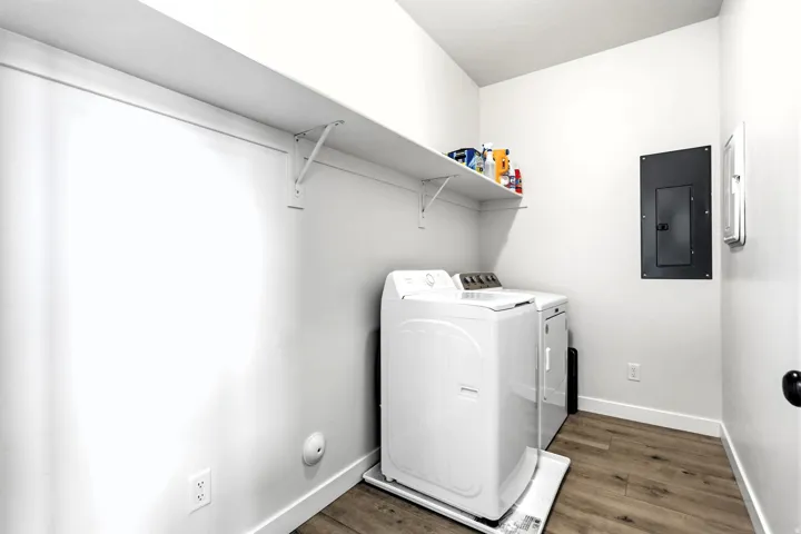 Main level laundry area with wood-finish flooring and a white shelving.