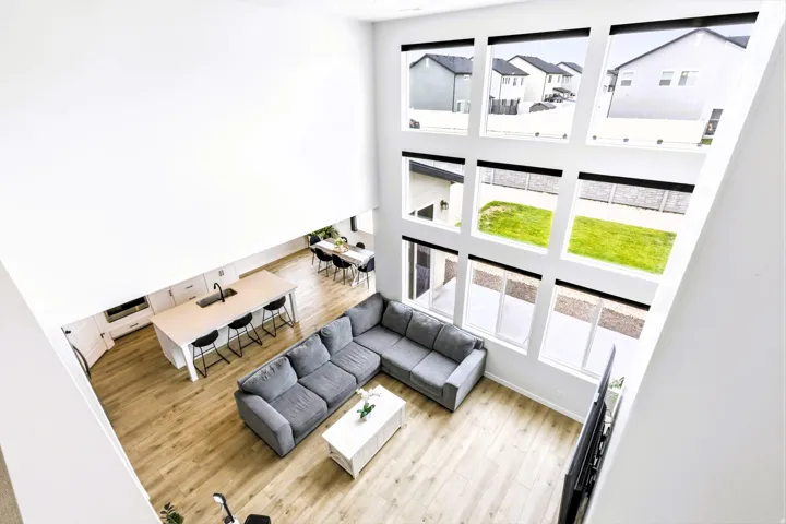 Open upstairs hallway with soaring ceiling, expansive window wall, light wood-finish flooring.