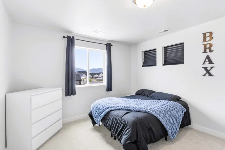 Bedroom #3 featuring expansive windows with mountain views, dark gray grommet curtain panels, white dresser with multiple drawers, and neutral carpet flooring