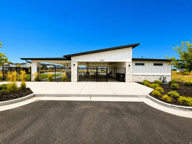 Community pool house that is gated and secure. Modern-style building with white siding and stone accents, featuring a covered entry and black fencing