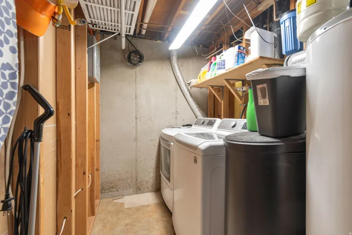 Laundry area featuring a side-by-side washer and dryer, concrete wall, and overhead lighting