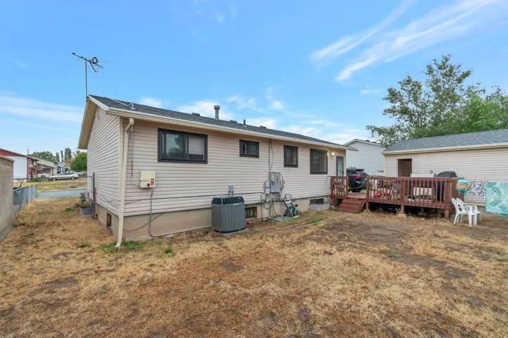Rear exterior with light-colored siding, a dark wood-finish deck, and a detached structure
