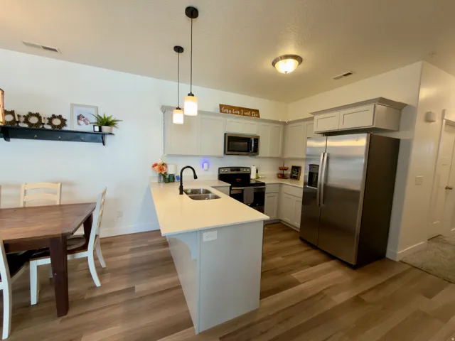 LVP flooring, white quartz countertops, built-in stainless steel appliances (all included), light gray cabinetry, and pendant lighting