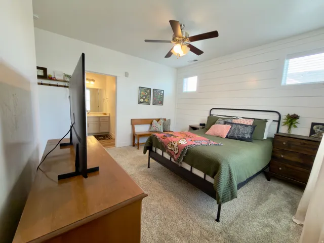 Large primary bedroom with 4 windows for ample light, ceiling fan & custom shiplap accent wall