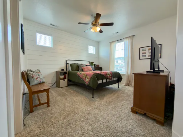 Large primary bedroom with 4 windows for ample light, ceiling fan & custom shiplap accent wall