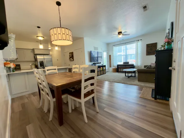 Open-concept living space with LVP flooring, a contemporary dining pendant light, ceiling fan, and recessed lighting