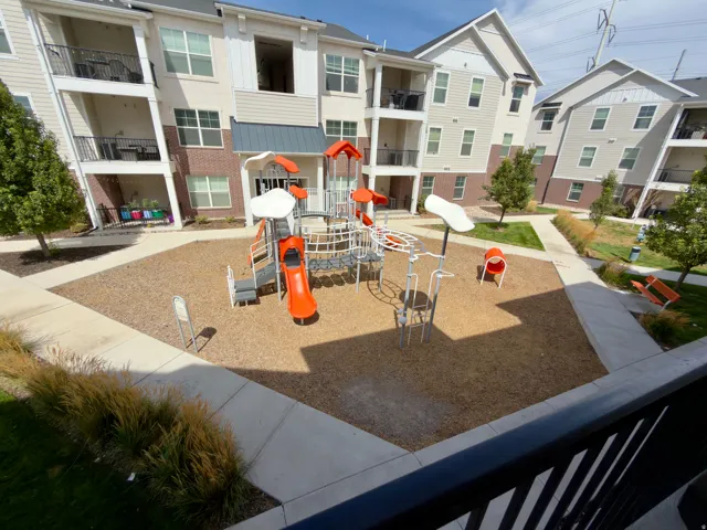 Central playground area just outside the condo featuring multiple slides, climbing structures, and ground-level seating
