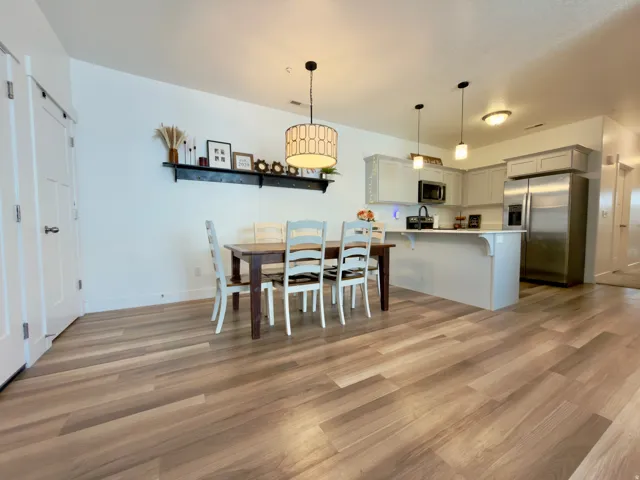 Open-concept kitchen and dining area featuring LVP flooring, a kitchen island with white quartz countertops, stainless steel appliances (included), and grey cabinetry