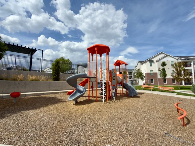 Playground area with wood chip surfacing, multiple slides, and climbing features
