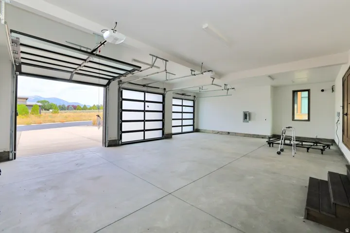 Three-car garage with concrete flooring, two full-panel opaque garage doors, and one glass-panel garage door