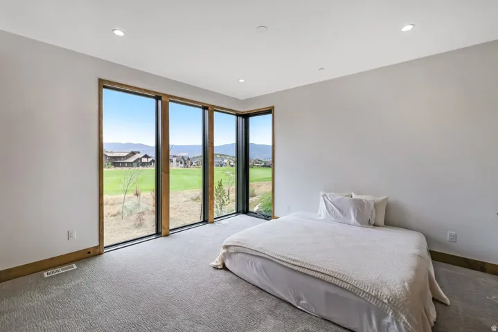 Recessed ceiling lighting, large window wall, wood-finish window frames, and carpeted flooring