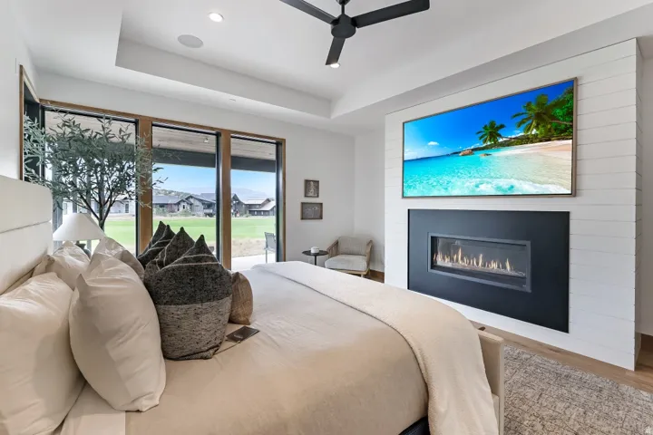 Recessed ceiling with integrated lighting, a black ceiling fan, and a built-in linear fireplace with a shiplap accent wall