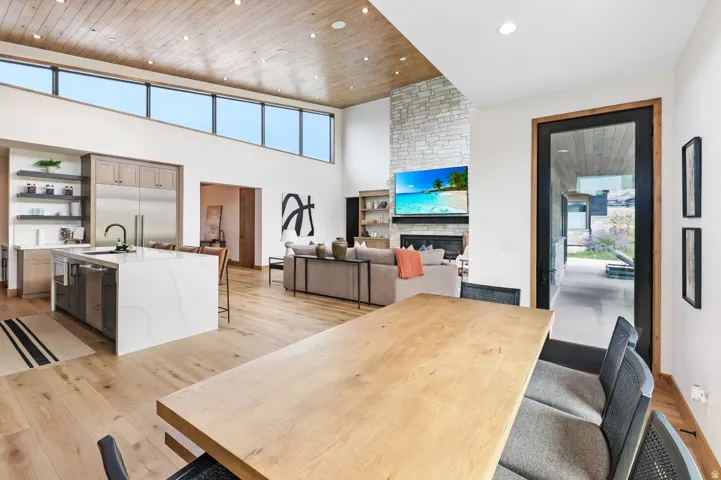 Open-concept living space with vaulted wood-plank ceilings, light wood-finish flooring, and high transom windows