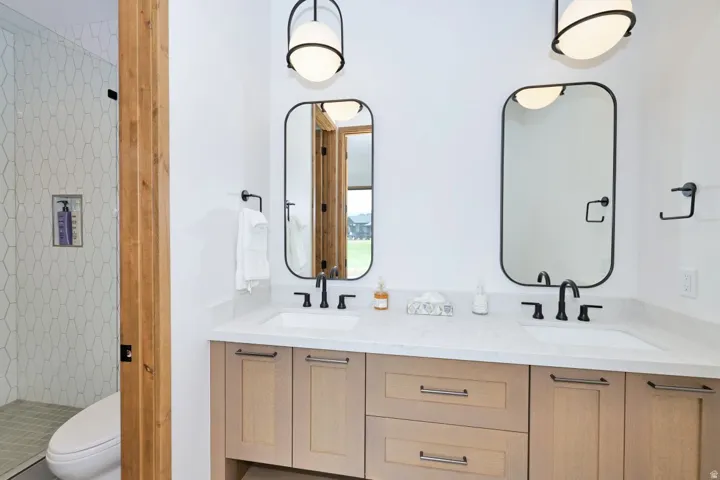 Dual vanity with undermount sinks, stone countertop, and matte black fixtures