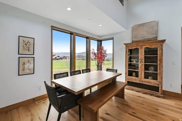 Expansive window wall with dark wood trim, wood-finish flooring, recessed lighting, and a built-in wooden display cabinet