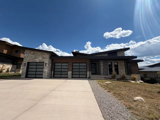 Contemporary exterior with stone veneer accents, multi-pane garage doors, and a concrete driveway